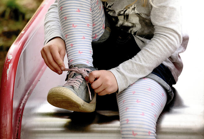 Barn sitter og knyter sko