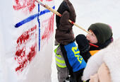 Unger som maler norsk flagg på snøen