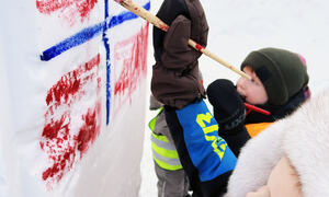 Unger som maler norsk flagg på snøen