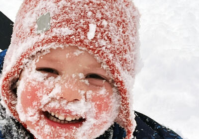 Barn med snø i ansiktet
