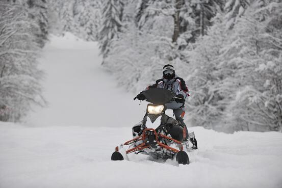 Mann på snøscooter ute i naturen