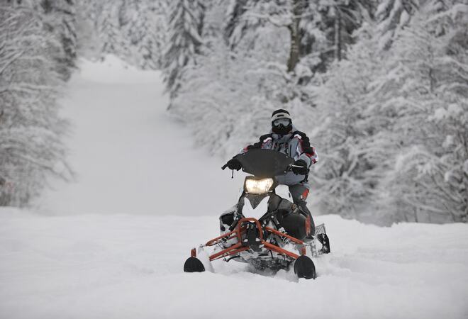 Mann på snøscooter ute i naturen