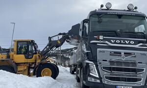 Hjullaster dumper snø i lasteplanet på lastebil.