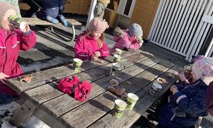 Barn sit rundt bort og drikk saft og et kaker i sola.