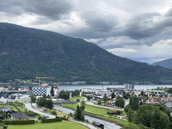 Sogndal. (Foto: Mariann Skau) Bilete av elv, tre, fjell, fjord og store bygningar, mellom dei Quality Hotel.