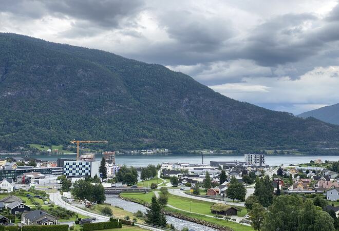 Bilete av elv, tre, fjell, fjord og store bygningar, mellom dei Quality Hotel.