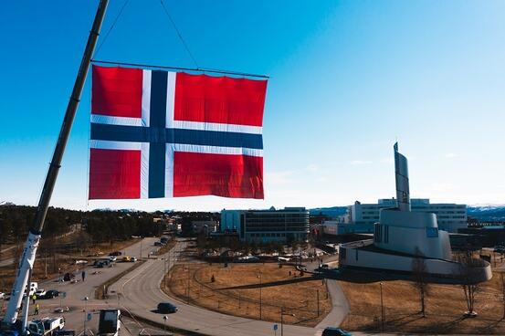 Stort norsk flagg med Nordlyskatedralen i bakgrunnen