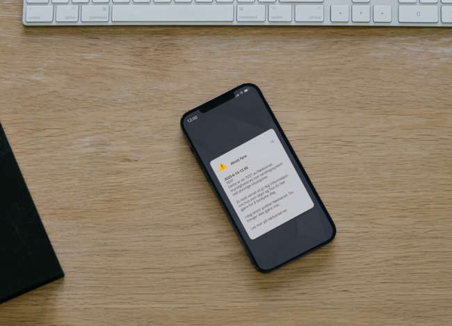 Mobiltelefon med melding om frå Nødvarsel, og med info om at det berre er ein test.