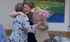 En kvinne overrekker en blomsterbukett til ordfører