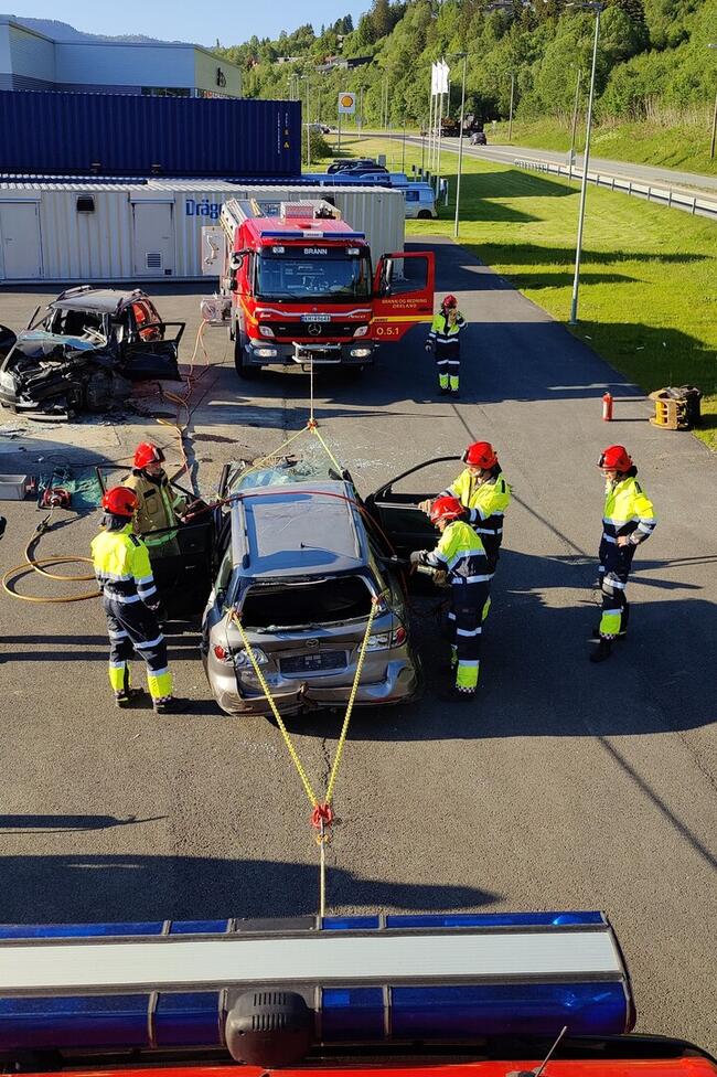 brann og redningsmannskaper jobber med en skadet bil