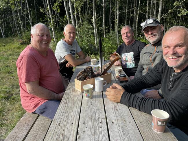 fem menn i fritidsklær rundt et bord