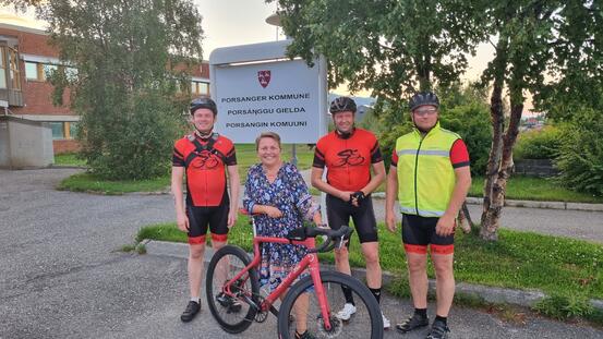 bilde av ordfører og sykkelklubben med ARN-sykkelen forann skilt med Porsanger kommune