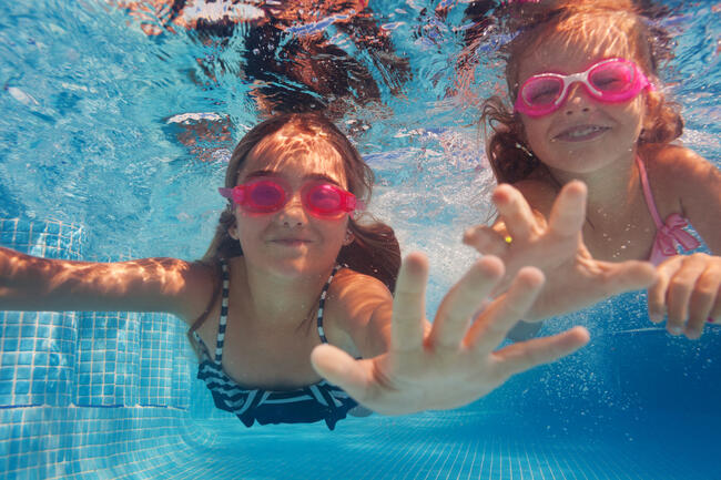 To jenter i badetøy svømmer under vann
