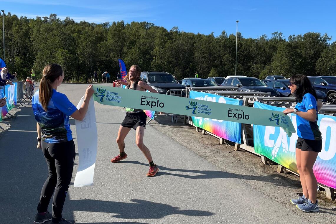 En veldig glad Stian Sommerseth er klar til å bryte målseilet som vinner av NM terrengultra. (Arrangørfoto)