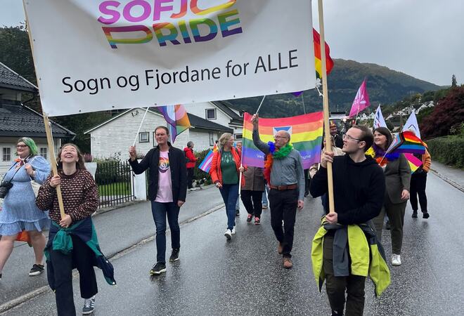 Personar som går i tok med parolen Sogn og Fjordane for alle. Fleire har regnbogeflagg.