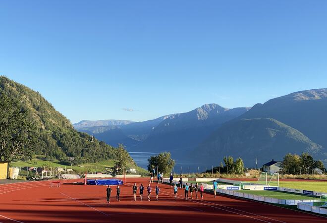 Løpebane med folk som spring, fjell og fjord. Anlegget er nybygd.