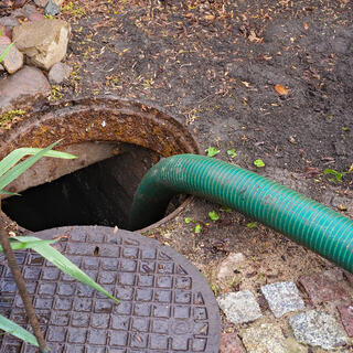Bilde av åpent kumlokk med slange for tømming av septik