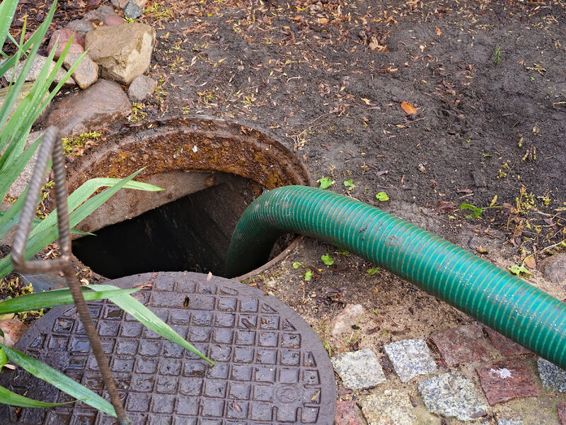 Bilde av åpent kumlokk med slange for tømming av septik