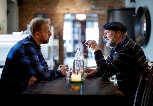 To menn som snakker med hverandre ved et bord med levende lys