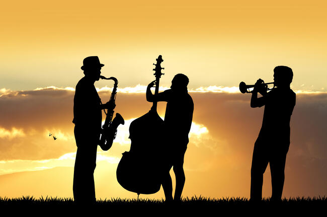 tre jazzmusikere i siluett mot en solnedgang