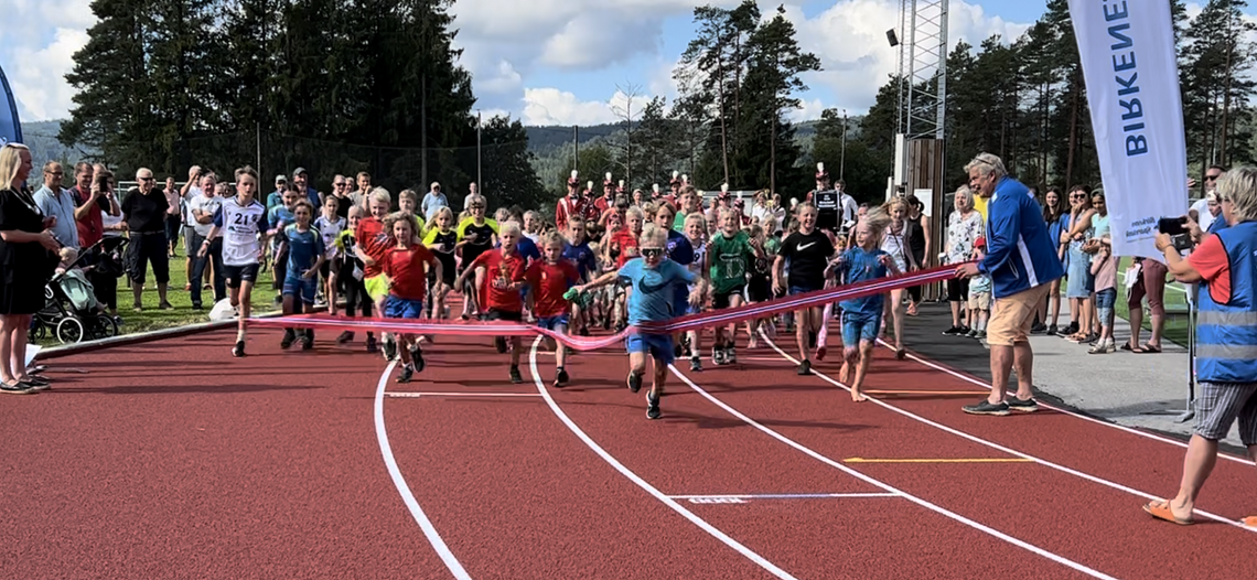 Fra åpningen av friidrettsanlegget i Birkenesparken 22. august 2022 der løpende barn fikk æren av å «løpe over startsnora» til tonene fra Birkeland Musikkorps. (Foto: Birkeland IL)