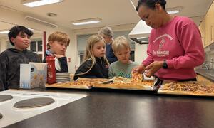 Olga Alstad deler ut pizza til barn