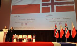 Scene med norske og polske flagg, to personar på talarstol.