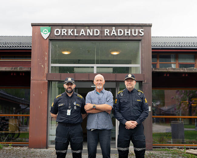 To menn i politiuniform og en i sivile klær foran Orkland rådhus.