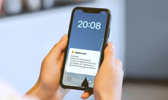 To hender holder en iPhone. Telefonen viser et eksempel på nødvarsel. Klokken på telefonen viser 20:08.