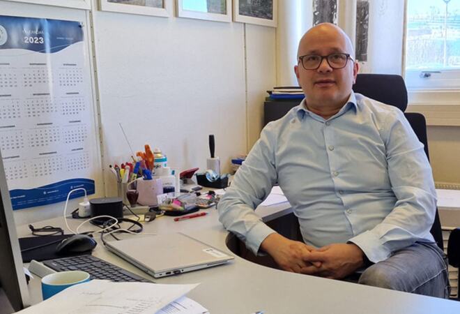 Foto av kommunedirektør Charles Petterson sittende ved en kontorpult.