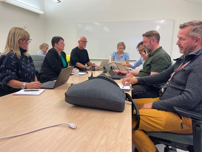 En alvorlig samling av mennesker rundt et bord