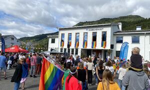 Ved kommunehuset. Store og små prideflagg og mykje folk.