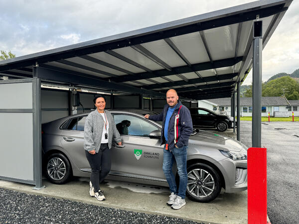 Her står avdelingsleder Mona Sommervold sammen med kommunens bilansvarlig, Erling Bjørkli. De poserer foran hjemmetjenestens carporter. Foto: Jonas Olsen Withbro/Orkland kommune