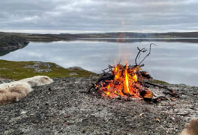 Bilde av bål ved en speilblank sjø