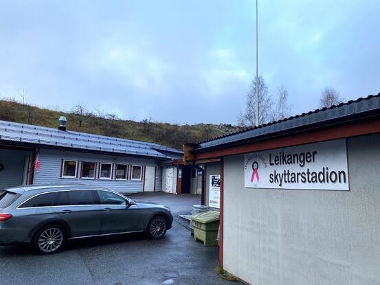 Skyttarhuset til venstre, og skytebaneanlegget ut i ein vikel frå det. Skilt med Leikanger skyttarstadion.