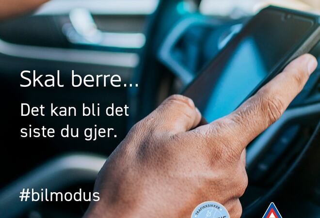 Ein person som kjører bil og samtidig held mobiltelefonen i handa