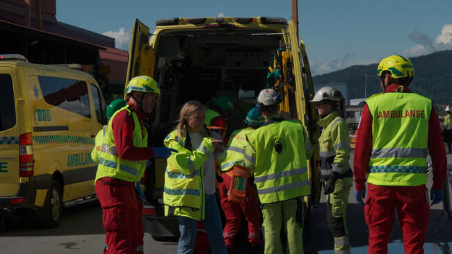 Bildet er tatt fra LRS-øvelse (Lokal redningssentral) i Orkland i 2024. Det viser rundt seks ambulansearbeidere i aksjon. De har på seg gule jakker og hjelm. Foto: Aksel Kjelbotn Wråli/Orkland kommune