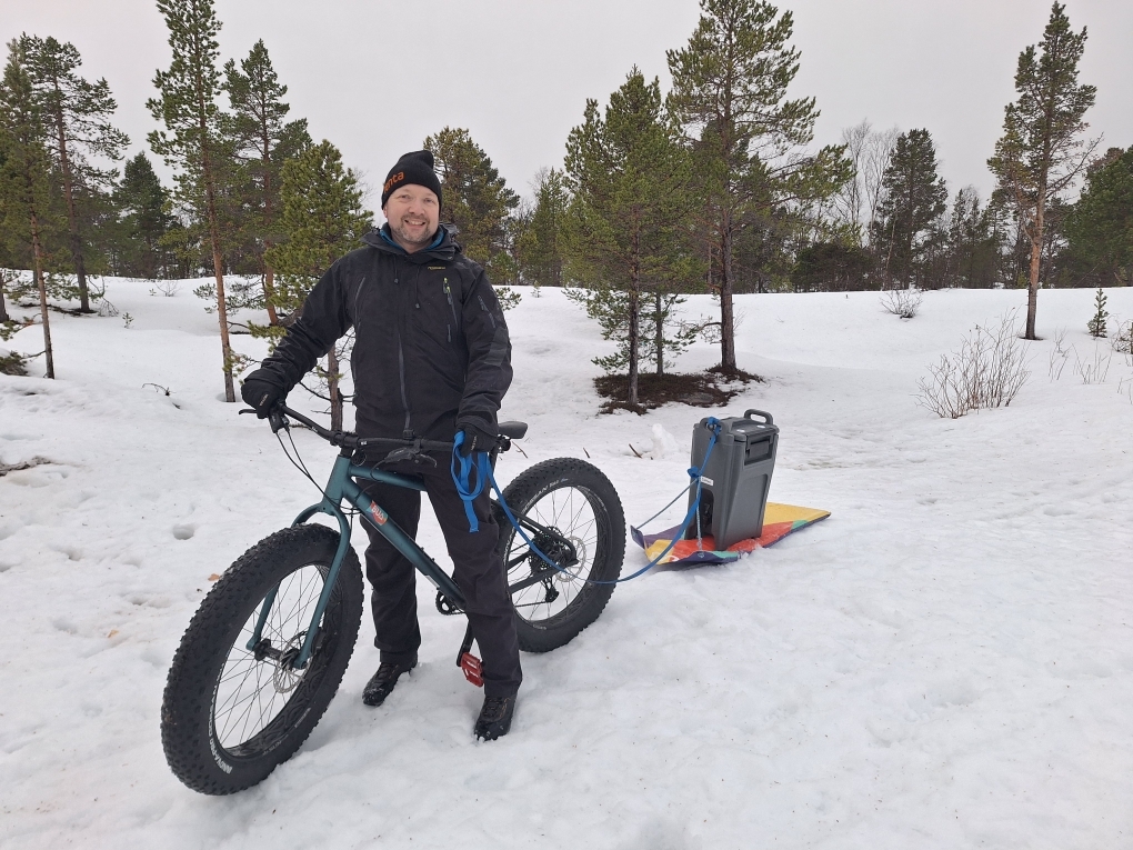 Mann på fatbike, har tauet akematte med container på, inneholdt kakao, til grillhytta.