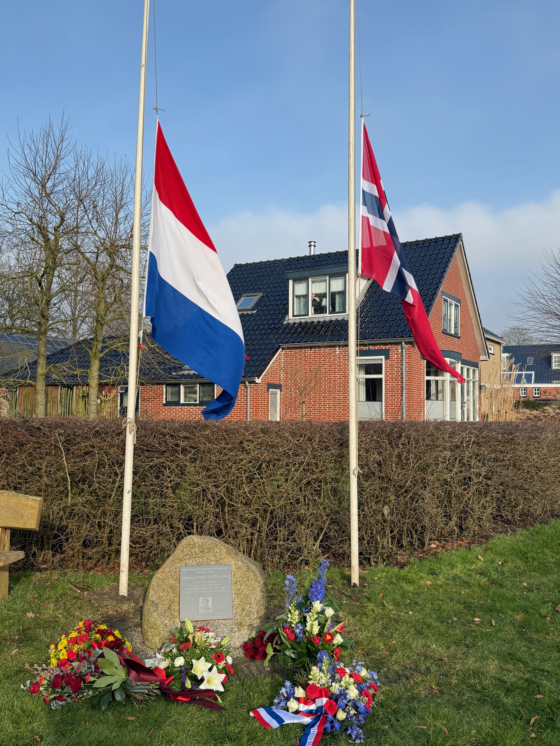 Minnesteinen i Eelde med de norske og nederlandske flaggene vaiende på halv stang