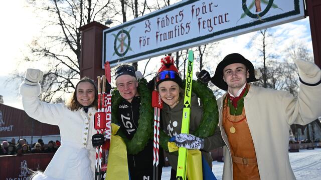 Alvar Myhlback og Stina Nilsson sammen med dagens kranskulla og kransmas under den kjente målportalen i Mora. (Foto: Arrangøren)