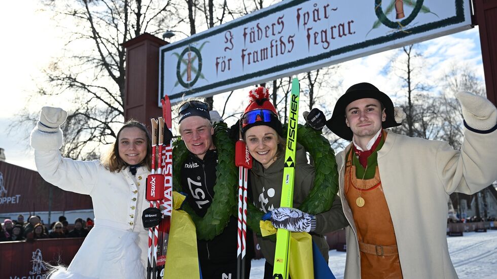 Alvar Myhlback og Stina Nilsson sammen med dagens kranskulla og kransmas under den kjente målportalen i Mora. (Foto: Arrangøren)