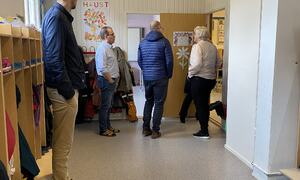 Fem personar, rektor og politikarar i gangen.