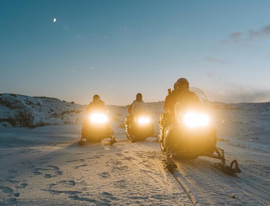 Foto av 3 snescootere i skumring