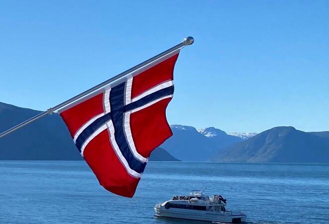 Balkongflagg, musikkbåt på fjorden, fjell og blå himmel