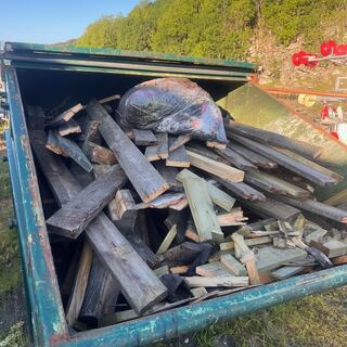 en grønn container som er fylt opp med rivningstrevirke