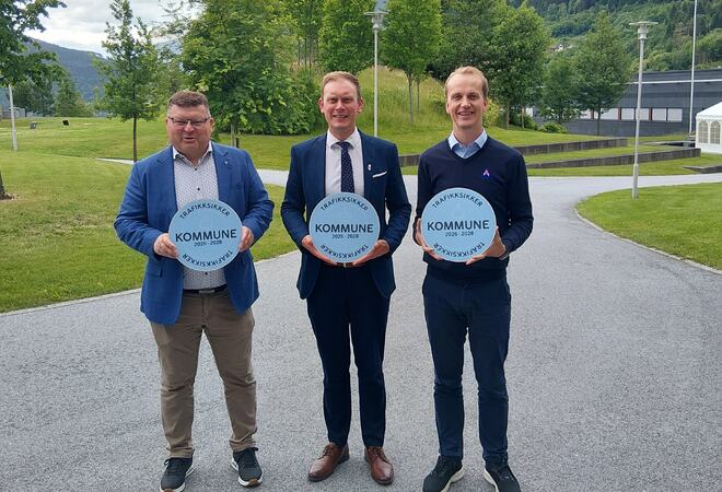 Tre menn står og held skilt med Trafikksikker kommune.