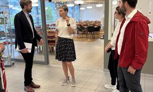 Mann i dress snakkar med kvinne i skjørt. To andre personar står og høyrer på.