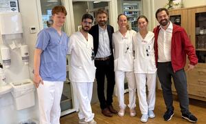 To menn i dress står smilande sman med med to kvinner og to menn i sjukepleiaruniformar