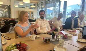 Fleire tilsette i Sogndal kommune sit ved eit bord saman med helseministeren