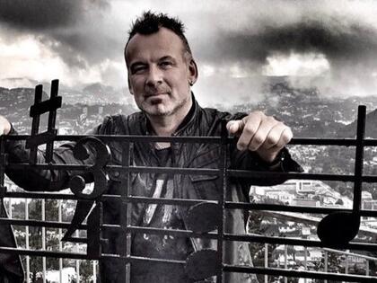 Tor Talle. Blide av Tor Talle som står ved eit notelinje-gjerde.